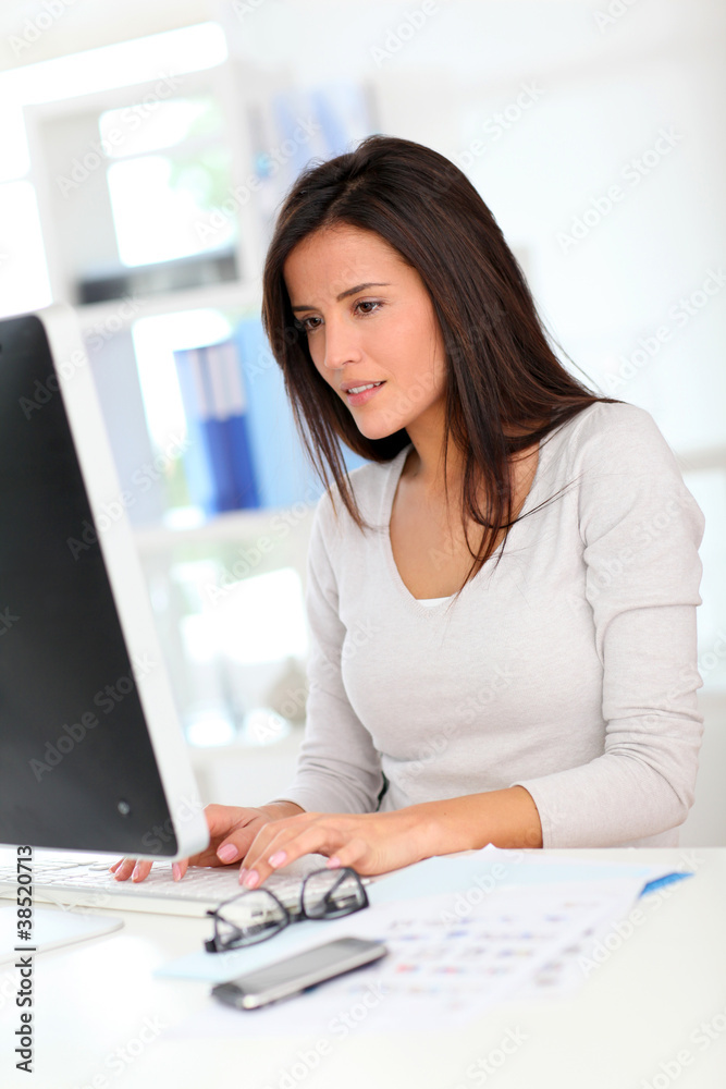Beautiful office worker in front of desktop computer Beautiful office worker in front of desktop computer
