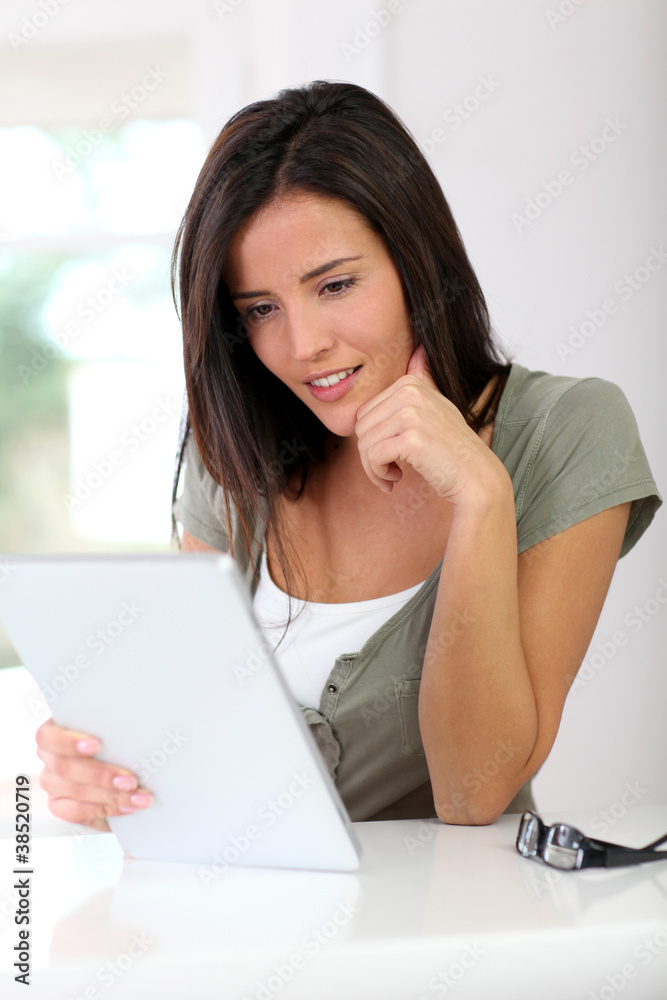 Smiling young woman working on electronic tablet at home Smiling young woman working on electronic tablet at home