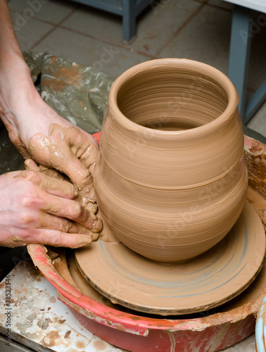 hands of a potter, creating an earthen jar on the circle