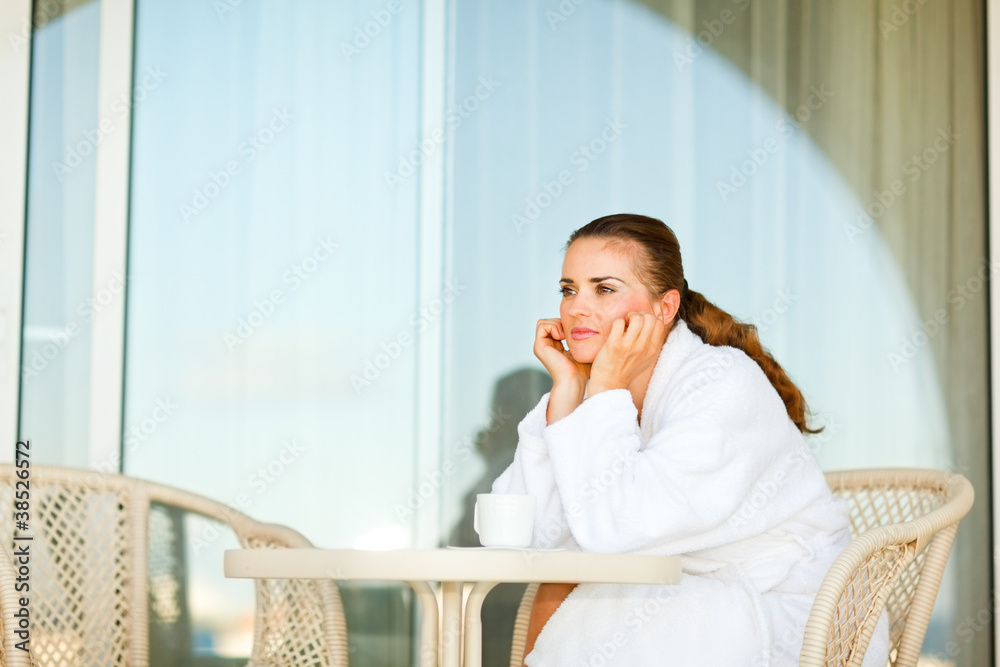 Beautiful woman in bathrobe sitting on terrace and dreaming Beautiful woman in bathrobe sitting on terrace and dreaming