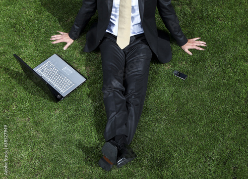 businessman sitting in a park with his laptop