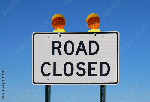 Road closed sign against a bright blue sky