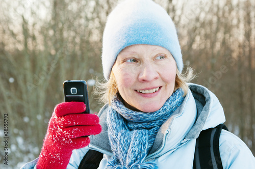 The woman photographes on a mobile phone in winter on walk photo