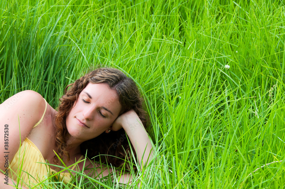 Country girl relaxing in a meadow of long green grass Country girl relaxing in a meadow of long green grass