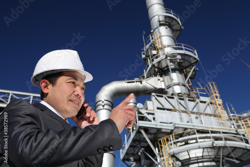 businessman calling under chemical plant tower