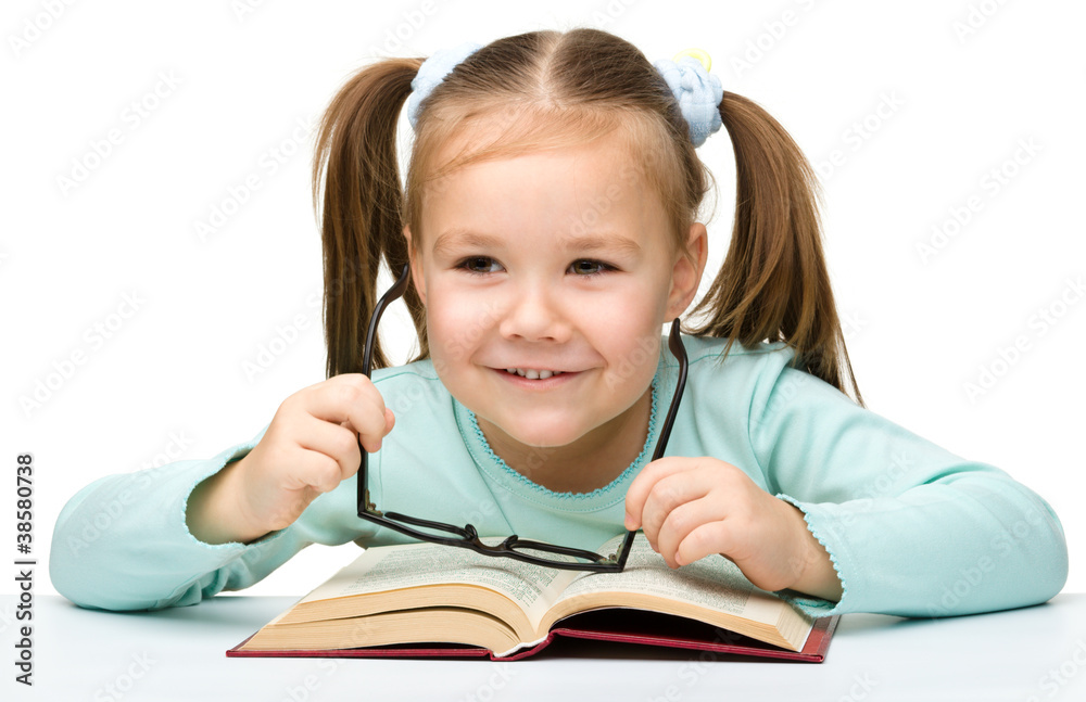 Little girl reads a book while wearing glasses Little girl reads a book while wearing glasses