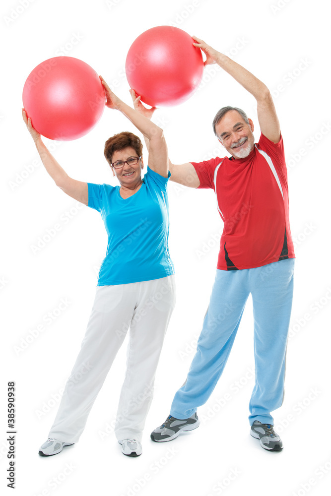 Senior couple doing fitness exercise with a ball in gym Senior couple doing fitness exercise with a ball in gym