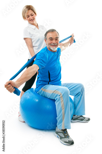 Senior man doing fitness exercise with help of trainer