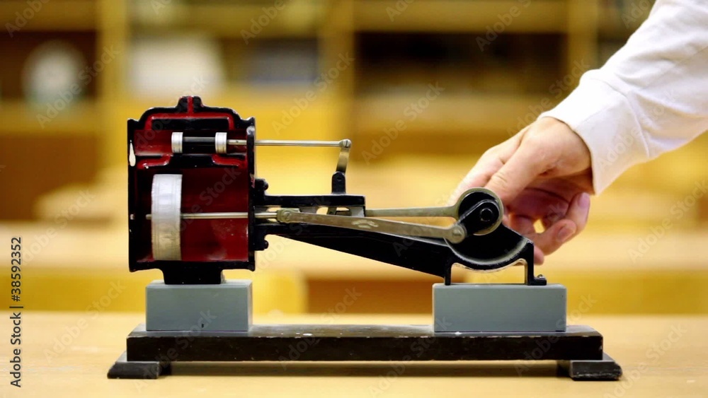 Man rotates model of steam engine in physics school class