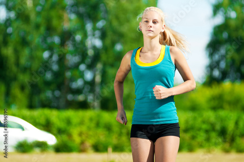 Young woman running in green park