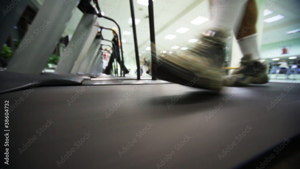feet of man go on treadmill at large gym