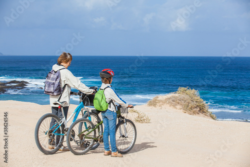 girl and her grandmother on bikes on the beach