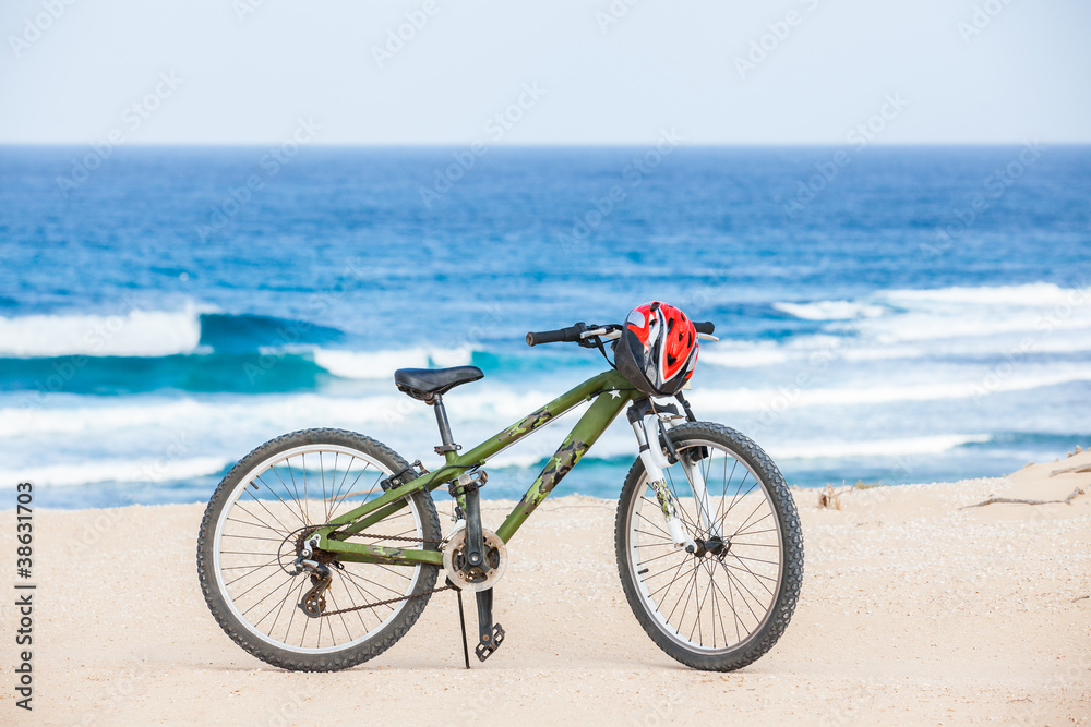 Obraz premium Bicycle with helmet, stand on the beach.