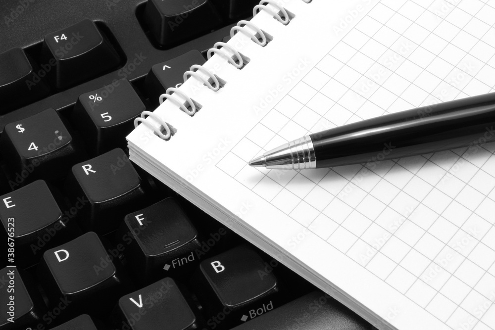 Notepad with pen on a black computer keyboard Notepad with pen on a black computer keyboard