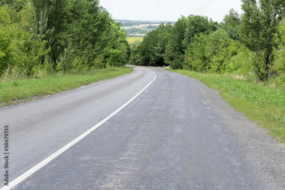 Fototapeta premium Empty curved road and trees in hilly district