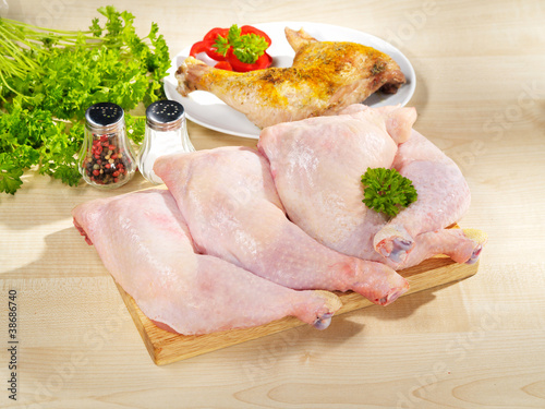 Fresh raw and roasted chicken legs arrangement on cutting board