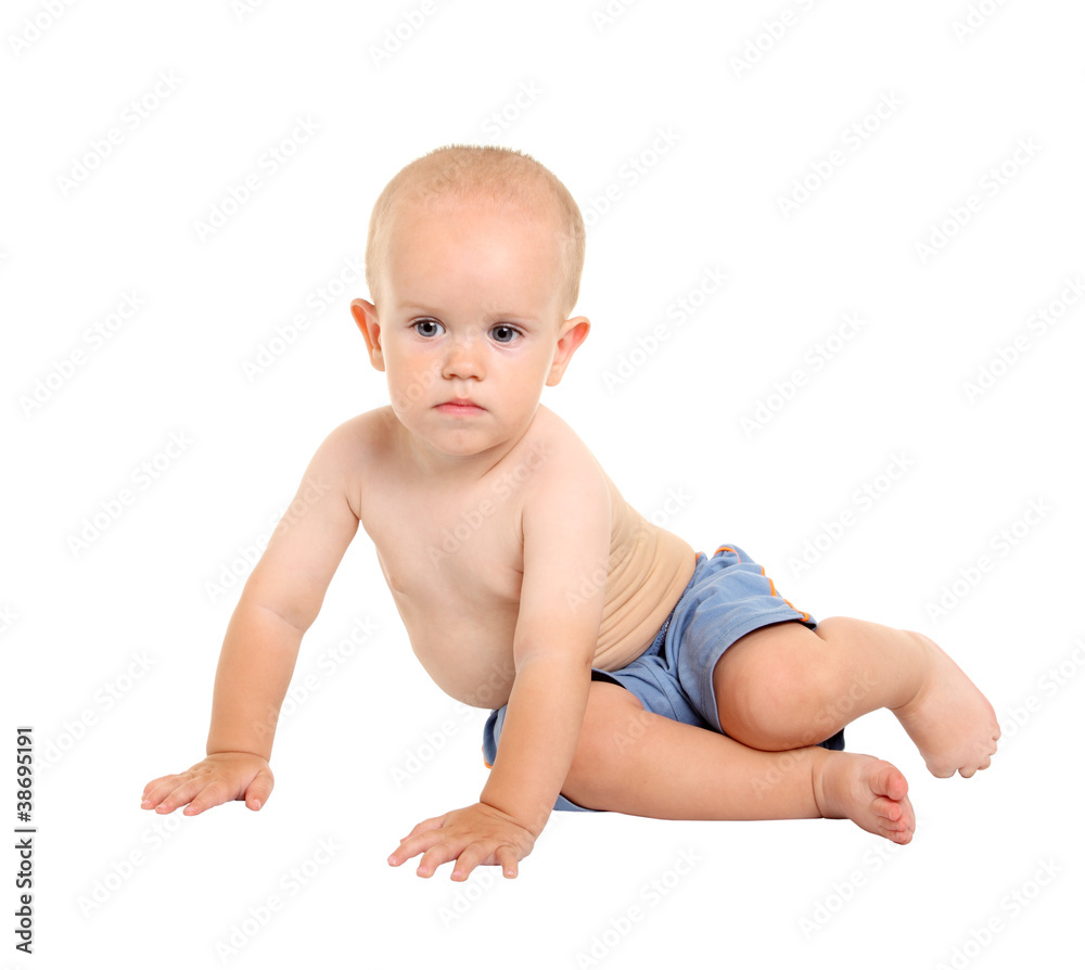 Baby in blue shorts, sitting on his knees on the white backgroun Baby in blue shorts, sitting on his knees on the white backgroun
