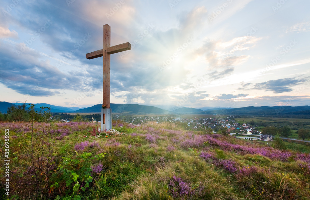 Summer evening country view with wooden cross