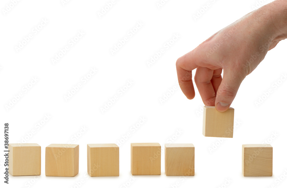 The hand establishes a wooden cube in row The hand establishes a wooden cube in row