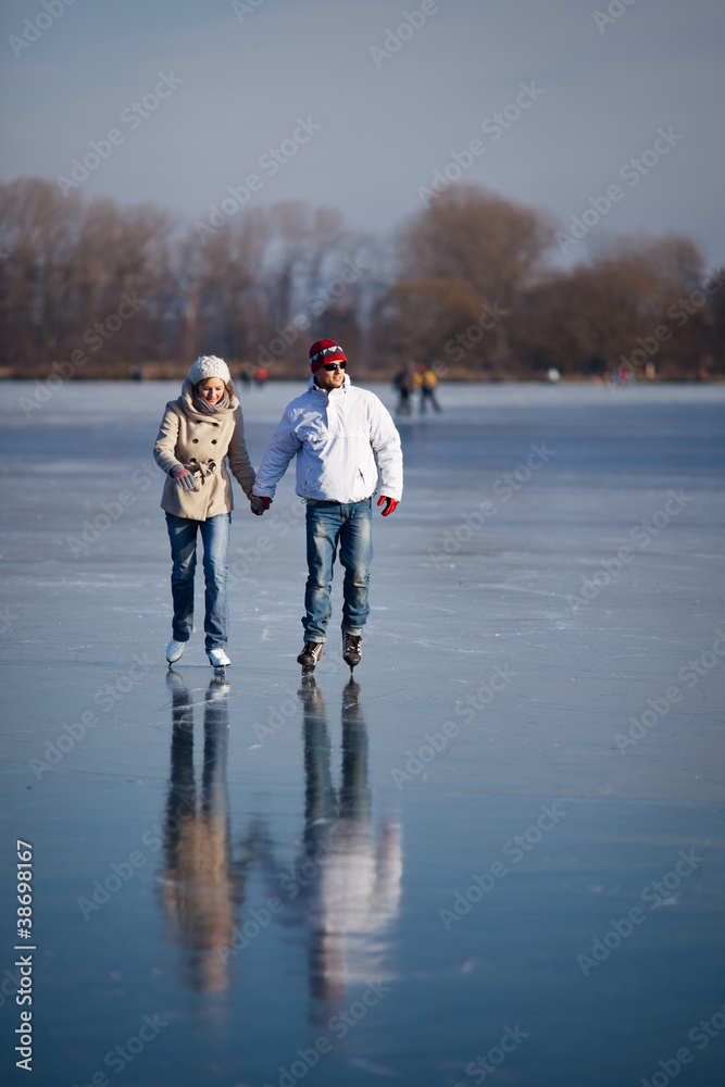 Couple ice skating outdoors on a pond on a lovely winter day