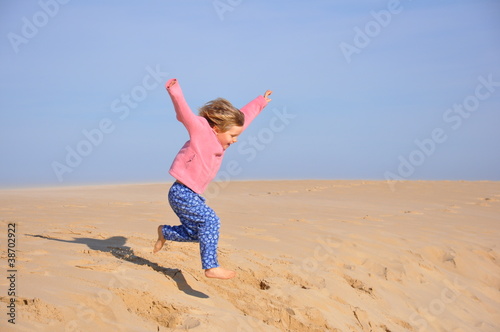 Fillette sautant d'une dune