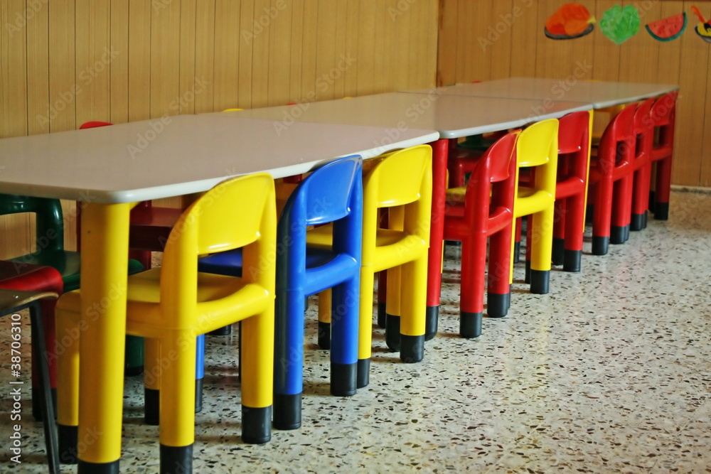colored row of empty chairs in a dining room of a kindergarten