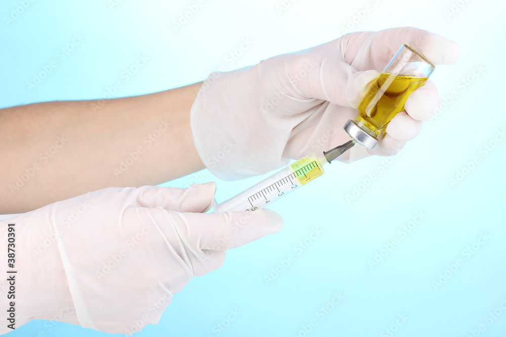 Syringe and medical ampoule in hands on blue background Syringe and medical ampoule in hands on blue background