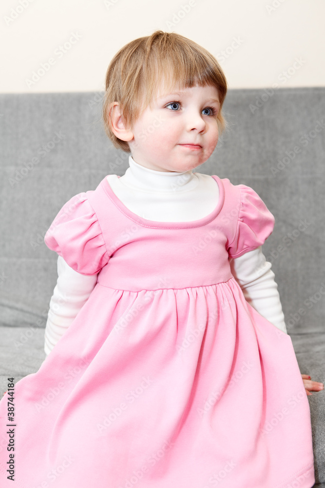 Portrait of small girl in pink dress sitting on couch Portrait of small girl in pink dress sitting on couch
