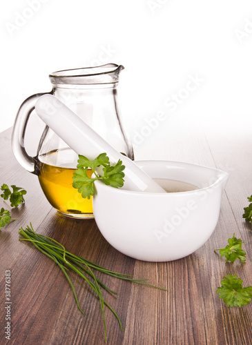 Mortar for herbs with olive oil on wooden background