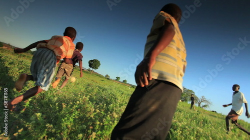 Happy children playing soccer, football on the fields in Africa.