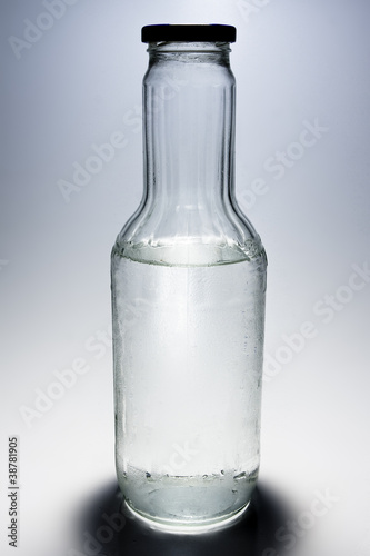 Wallpaper Mural Big glass bottle half filled with water on gray background Torontodigital.ca