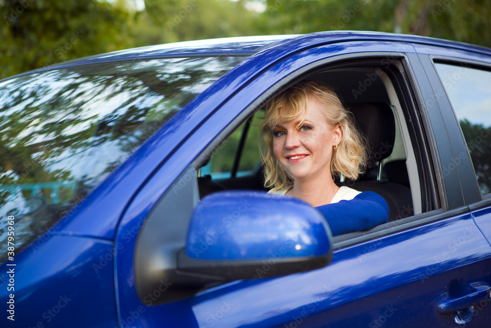 blonde woman sitting behind the wheel of a car