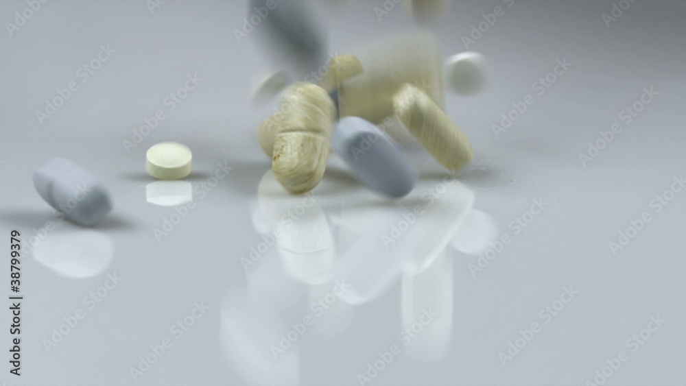 Supplement pills falling onto a pile.