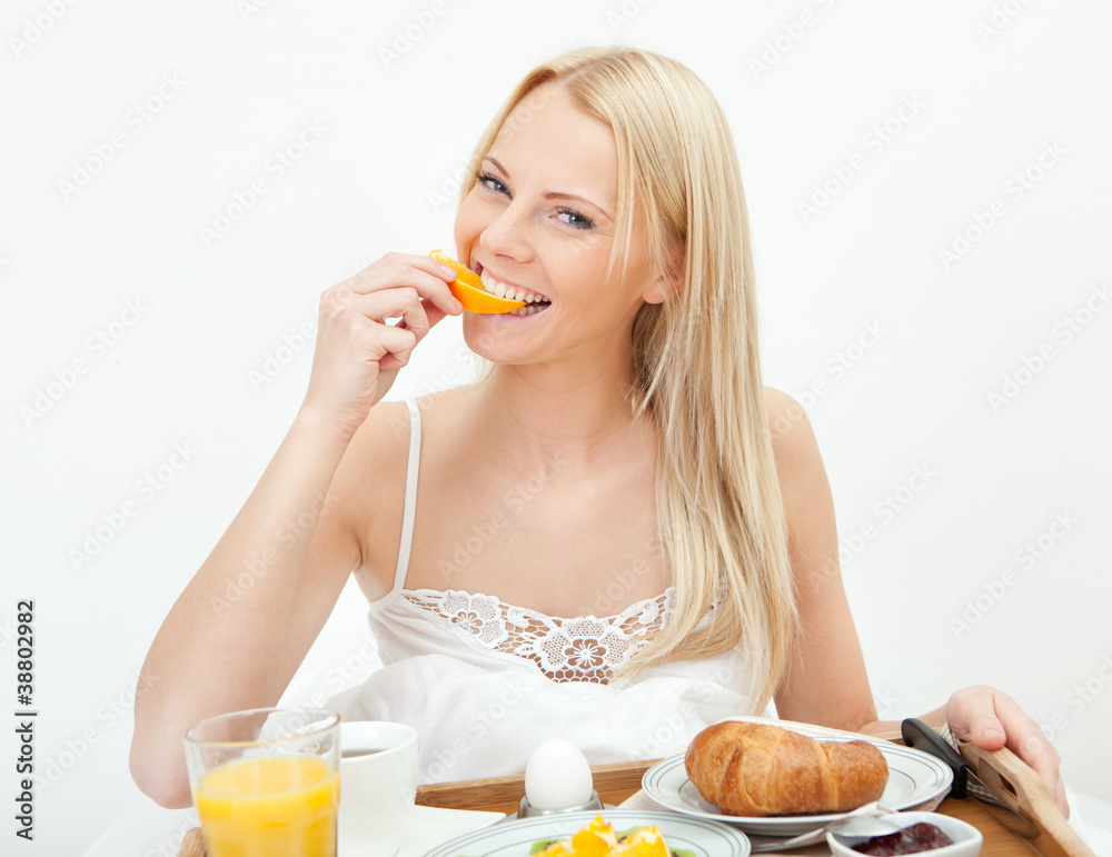 Beautiful woman eating orange in bed Beautiful woman eating orange in bed
