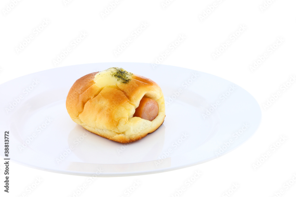 Sausage in bread and cheese on dish near view.