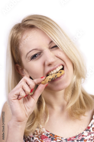 Young woman eating cookie with grimace