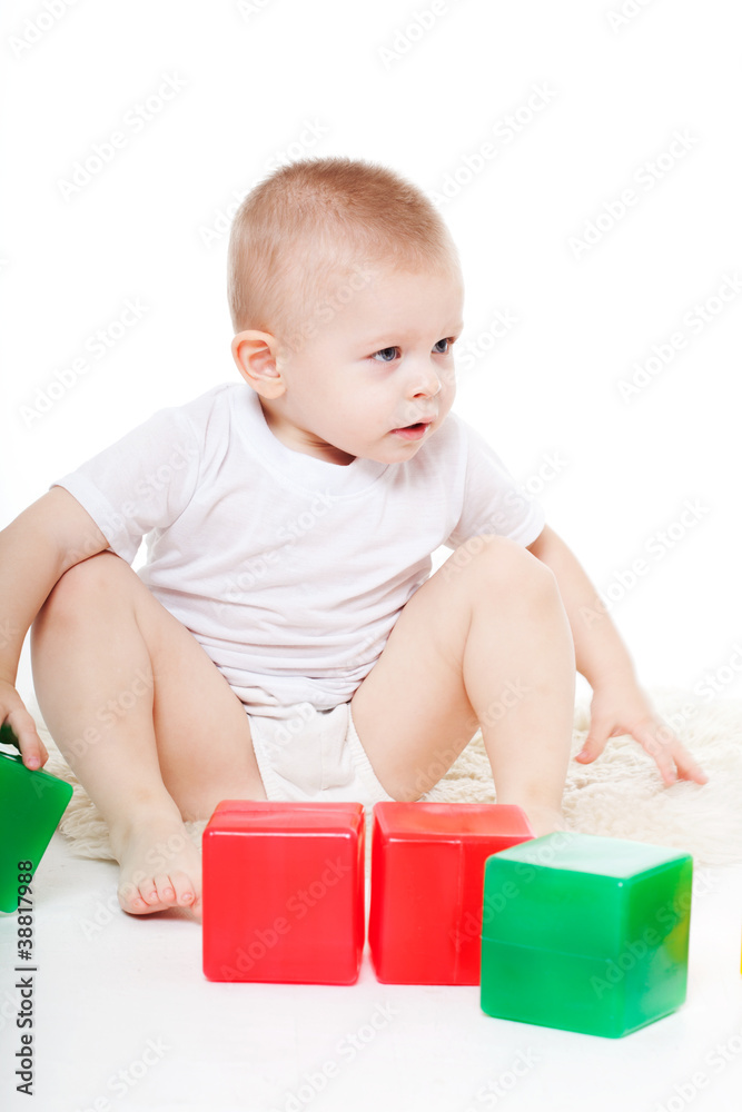 Baby boy plays with toy blocks over white background Baby boy plays with toy blocks over white background