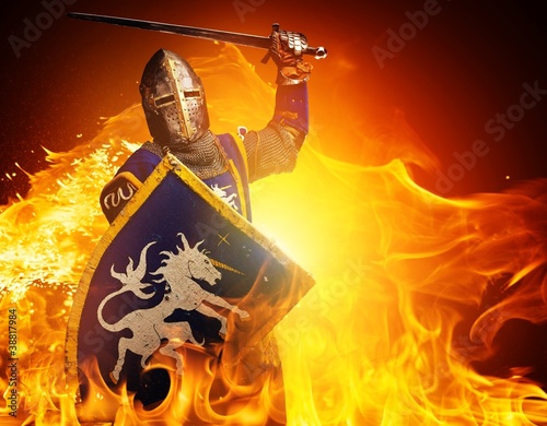 Medieval knight in attack position on fire background.
