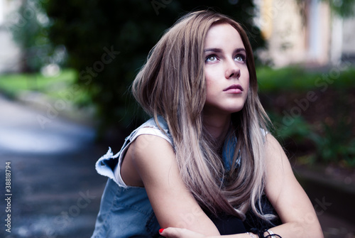 a beautiful young girl sitting sadly