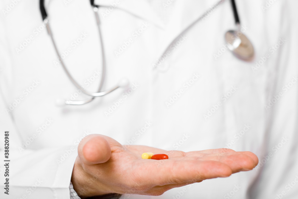 Doctor isolated on grey background offering pill on his palm Doctor isolated on grey background offering pill on his palm