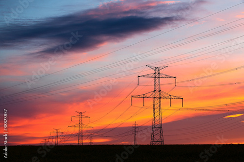 Transmission towers on the hills at red sunset © Radomir Rezny