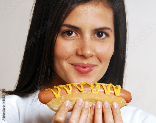 Joven mujer comiendo un hotdog.