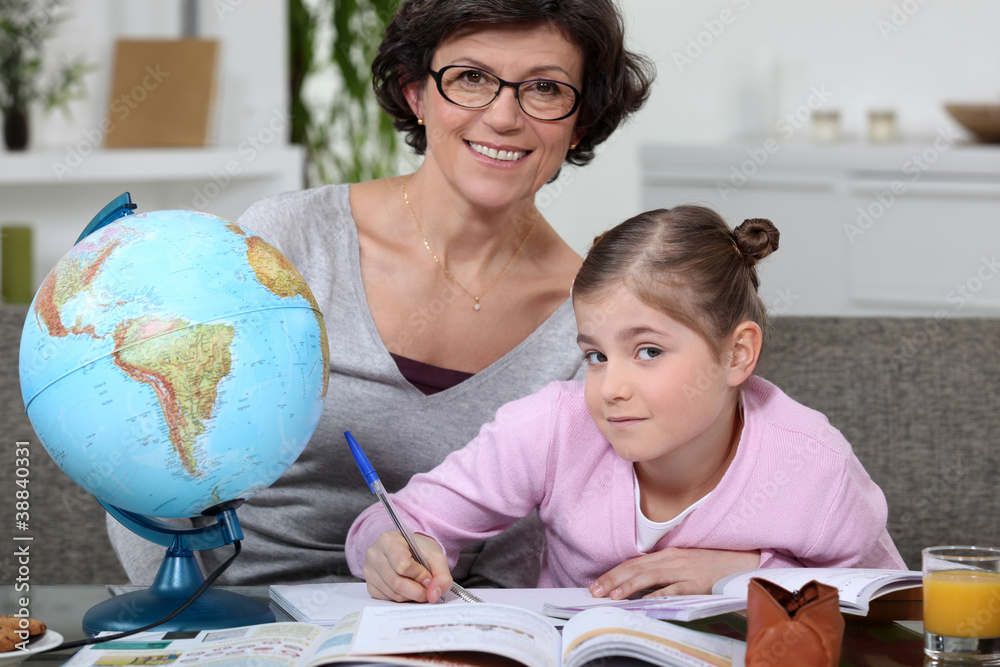 Fototapeta premium Little girl doing homework with her mom