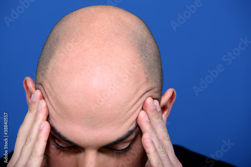 Bald man rubbing his temples