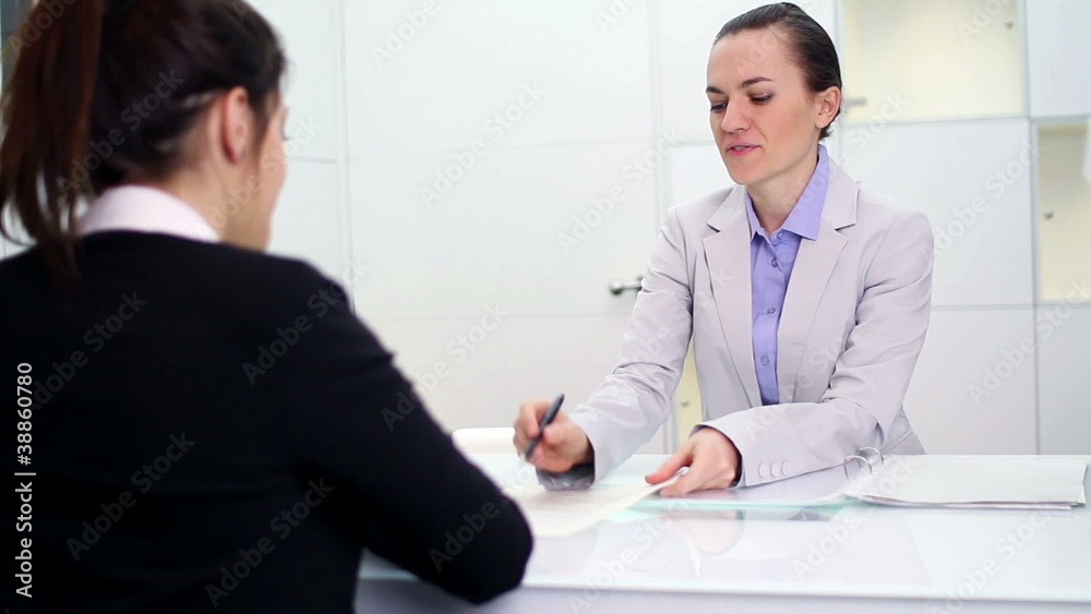 Young businesswoman signing contract with female client Young businesswoman signing contract with female client