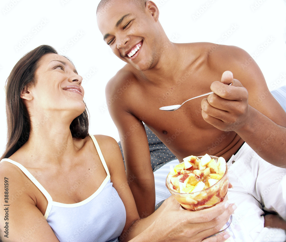 Pareja hispana compartiendo y comiendo ensalada de frutas. Pareja hispana compartiendo y comiendo ensalada de frutas.