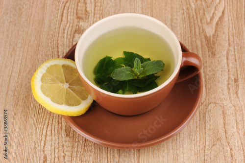 Mint tea with mint leaf and lemon on wooden background