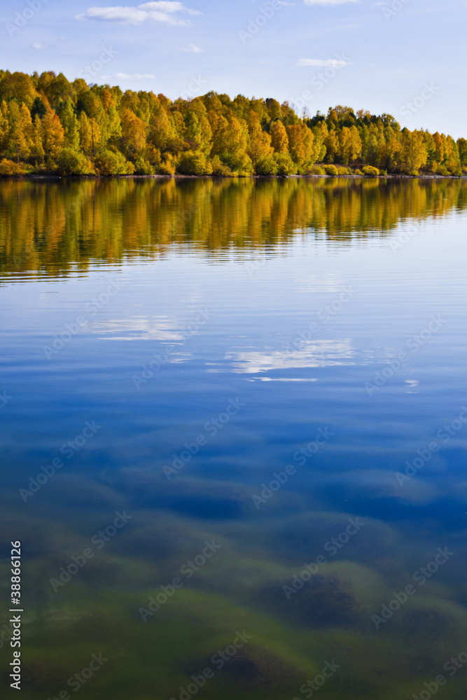 Autumn shoreline with beautiful clouds and reflections in calm w