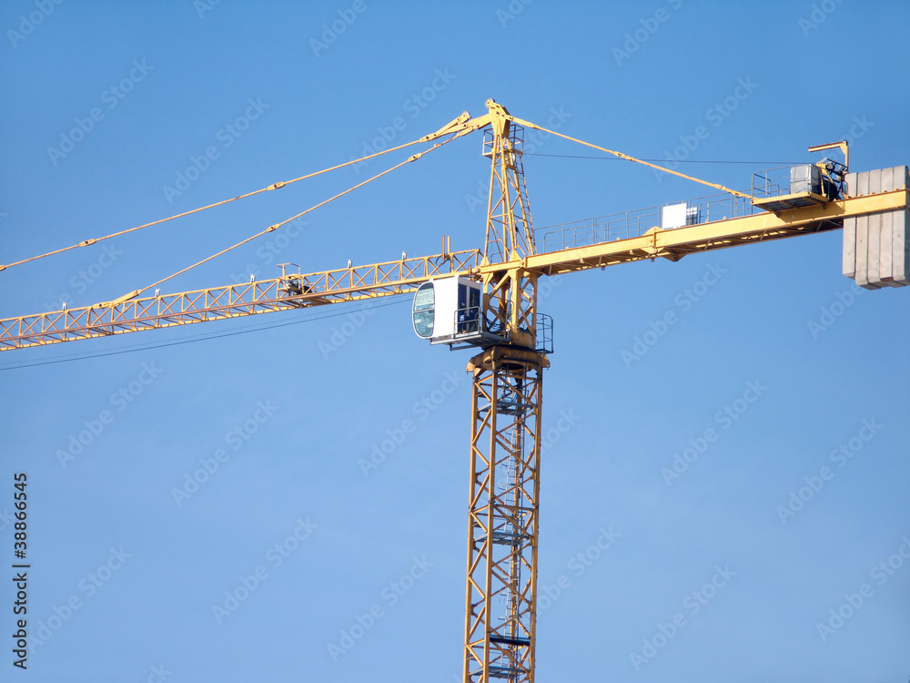 Yellow construction hoisting crane over blue sky