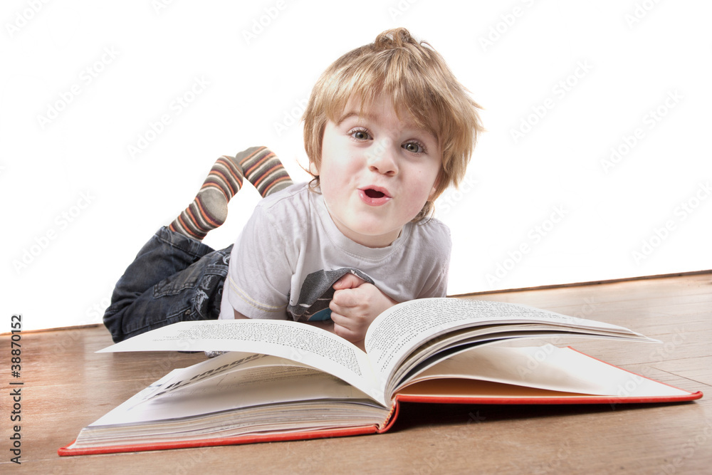 boy laying on floor pulling a funny face whilst reading book boy laying on floor pulling a funny face whilst reading book